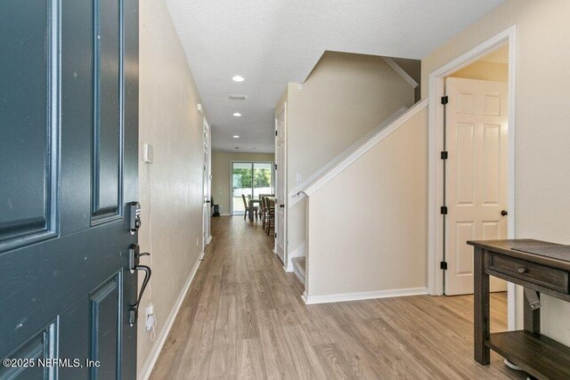 foyer entrance with light wood finished floors, baseboards, recessed lighting, and stairs