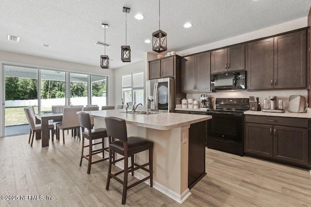 kitchen with dark brown cabinets, a wealth of natural light, a sink, and black appliances