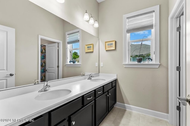 bathroom with tile floors, dual sinks, vanity with extensive cabinet space, and a wealth of natural light