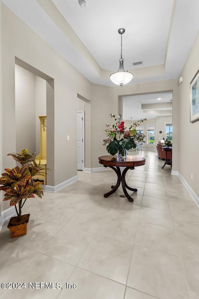 hall featuring tile flooring and a raised ceiling