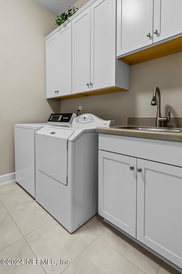 laundry area with cabinets, sink, washing machine and dryer, and light tile flooring