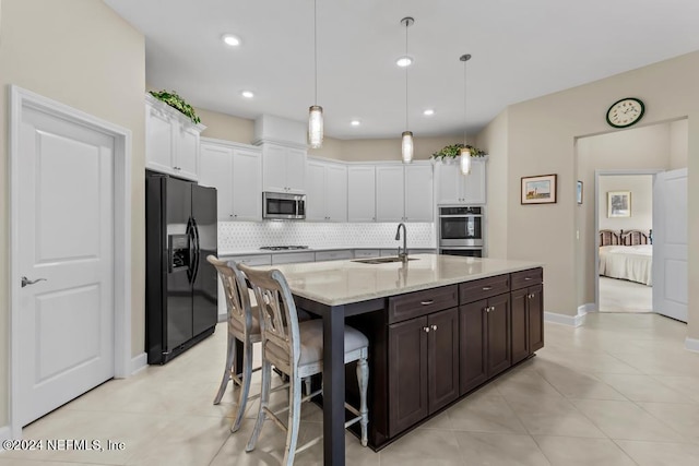 kitchen with appliances with stainless steel finishes, white cabinets, tasteful backsplash, and hanging light fixtures