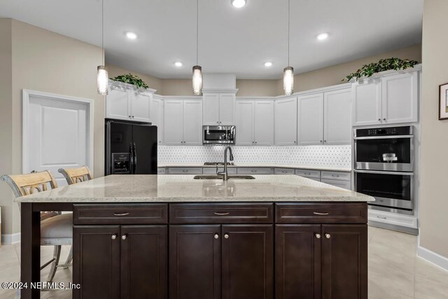 kitchen featuring backsplash, white cabinets, a breakfast bar area, and stainless steel appliances