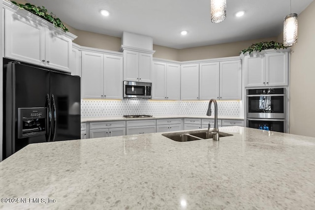 kitchen with decorative light fixtures, tasteful backsplash, white cabinetry, appliances with stainless steel finishes, and sink