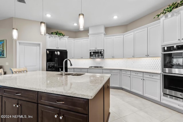 kitchen with decorative light fixtures, stainless steel appliances, tasteful backsplash, white cabinets, and sink