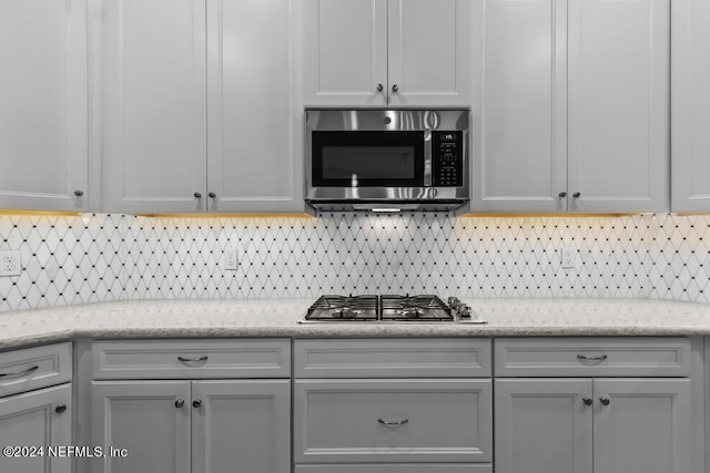 kitchen with stainless steel appliances, light stone countertops, and tasteful backsplash