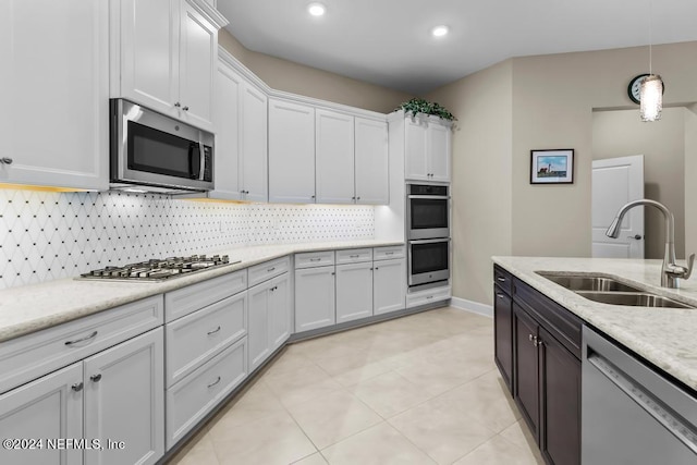 kitchen featuring stainless steel appliances, white cabinets, backsplash, sink, and light tile flooring