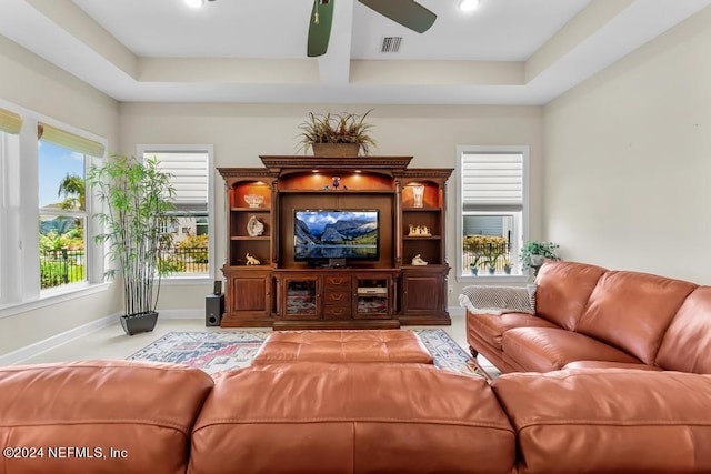 living room with a raised ceiling, ceiling fan, and carpet flooring