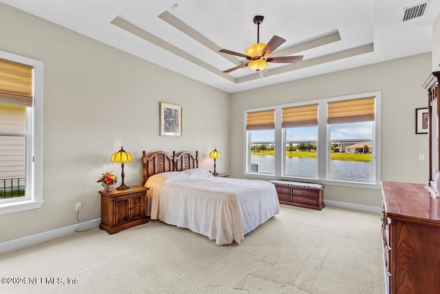 bedroom featuring carpet flooring, ceiling fan, a raised ceiling, and multiple windows