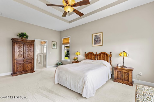 bedroom featuring ensuite bathroom, carpet, ceiling fan, and a tray ceiling