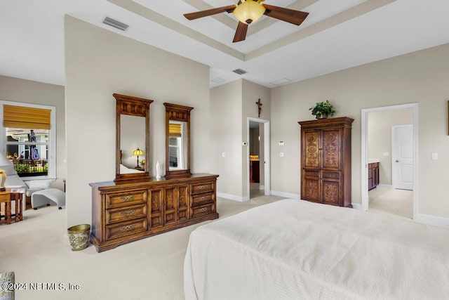 carpeted bedroom with ensuite bathroom, ceiling fan, a tray ceiling, and multiple windows