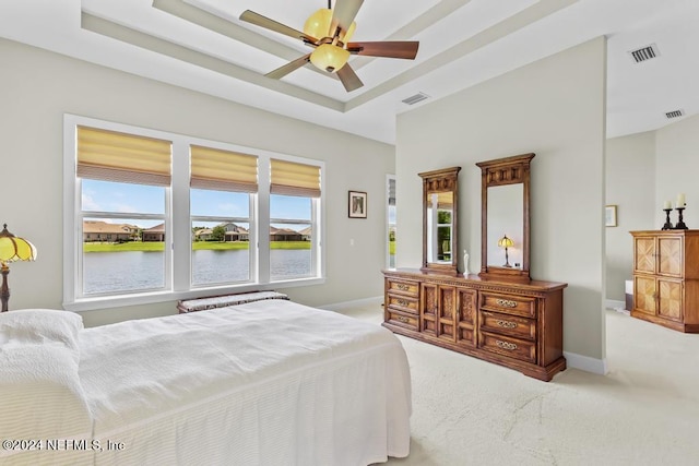 carpeted bedroom featuring ceiling fan, a raised ceiling, and multiple windows