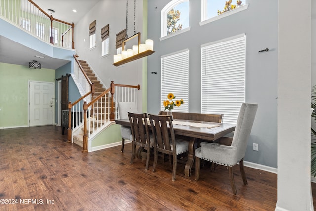 dining space with a towering ceiling and dark hardwood / wood-style floors