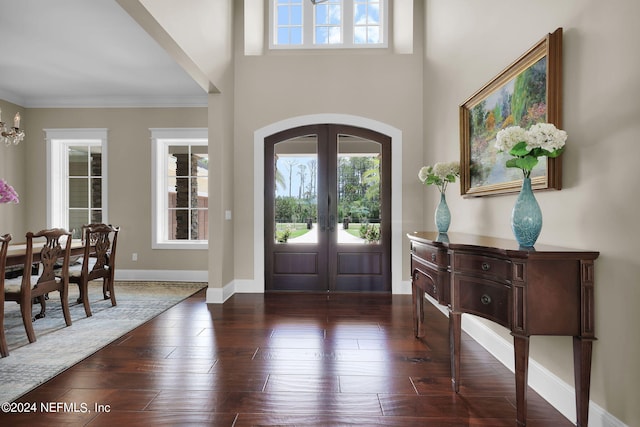 foyer with ornamental molding, plenty of natural light, a chandelier, and french doors