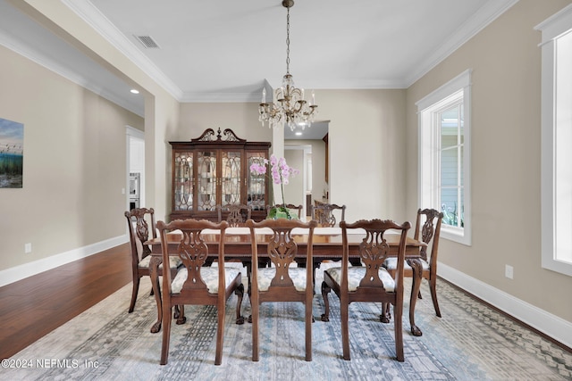 dining space featuring hardwood / wood-style flooring, crown molding, and a chandelier