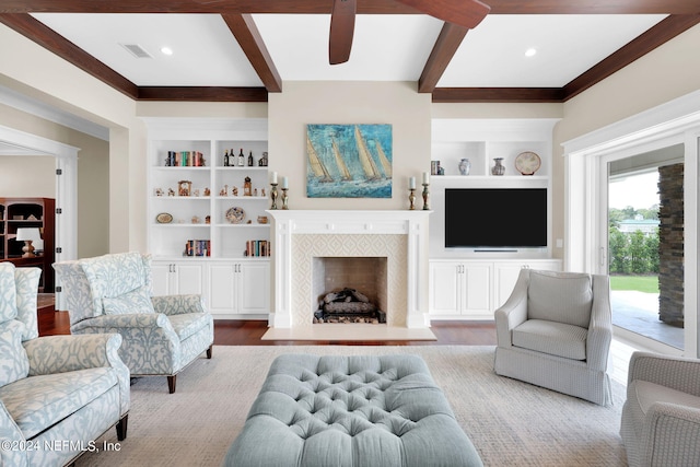 living room with wood-type flooring, beam ceiling, and built in shelves