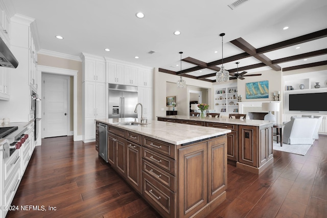 kitchen with dark brown cabinetry, white cabinetry, a center island with sink, appliances with stainless steel finishes, and beam ceiling