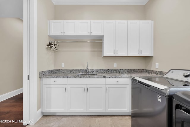 laundry room with sink, washer and clothes dryer, ornamental molding, and cabinets