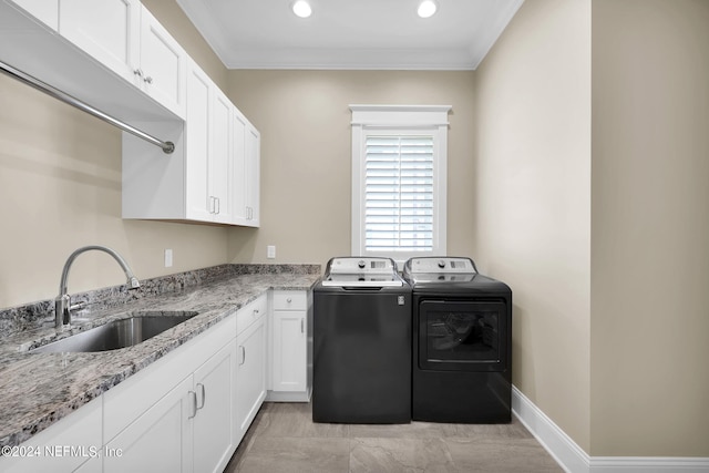 clothes washing area featuring crown molding, cabinets, sink, and washer and dryer