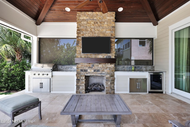 view of patio featuring a grill, area for grilling, wine cooler, an outdoor stone fireplace, and ceiling fan