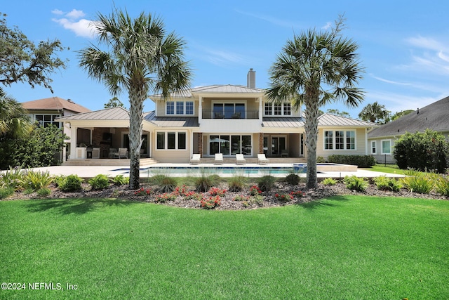 back of house with a balcony, a patio, and a lawn