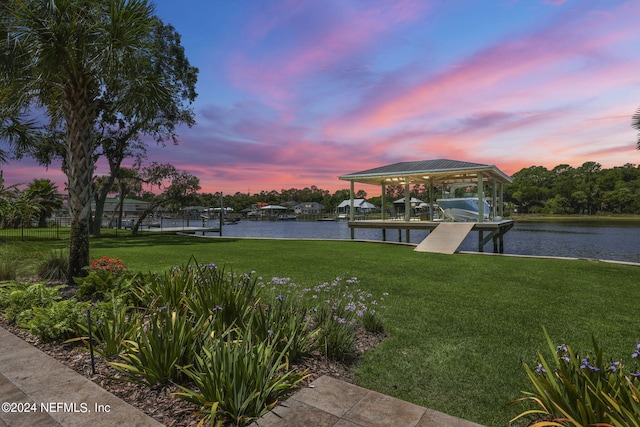 view of dock with a lawn and a water view