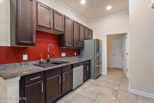 kitchen with appliances with stainless steel finishes, crown molding, sink, dark stone countertops, and light tile patterned flooring