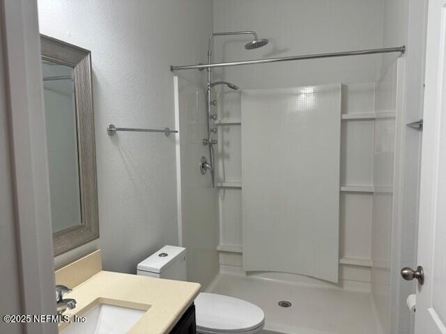 bathroom featuring a walk in shower, vanity, and toilet