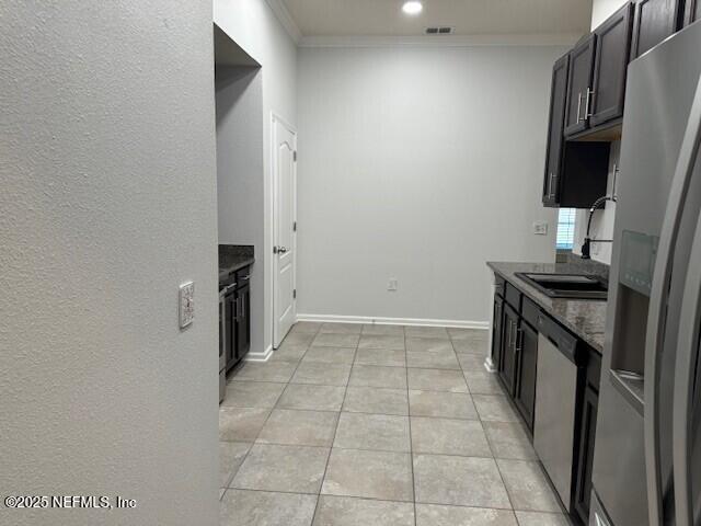 kitchen featuring light tile patterned floors, ornamental molding, stainless steel appliances, and dark stone countertops