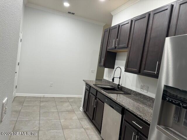 kitchen with crown molding, stainless steel appliances, visible vents, a sink, and dark stone counters