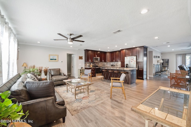 living room featuring light hardwood / wood-style flooring, a textured ceiling, crown molding, and ceiling fan