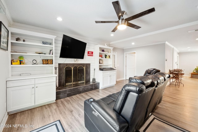 living room featuring ceiling fan, ornamental molding, light wood-type flooring, and a fireplace