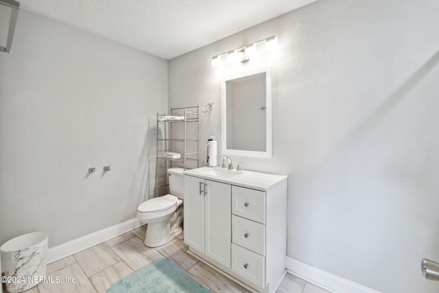 bathroom with vanity, toilet, and a textured ceiling