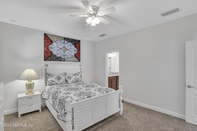 bedroom with ceiling fan, light carpet, and ensuite bathroom