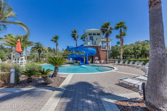 view of pool with a water slide and a patio area