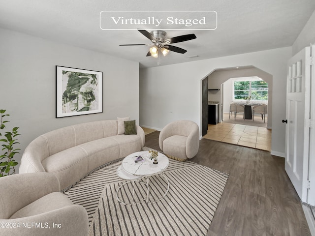 living room with dark wood-type flooring and ceiling fan