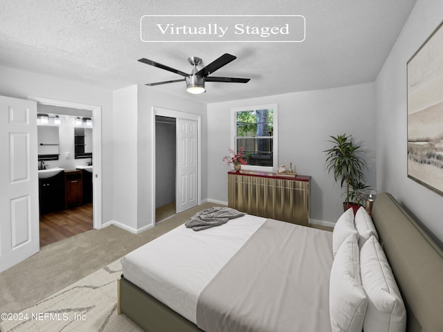 bedroom featuring ceiling fan, carpet flooring, a textured ceiling, sink, and connected bathroom