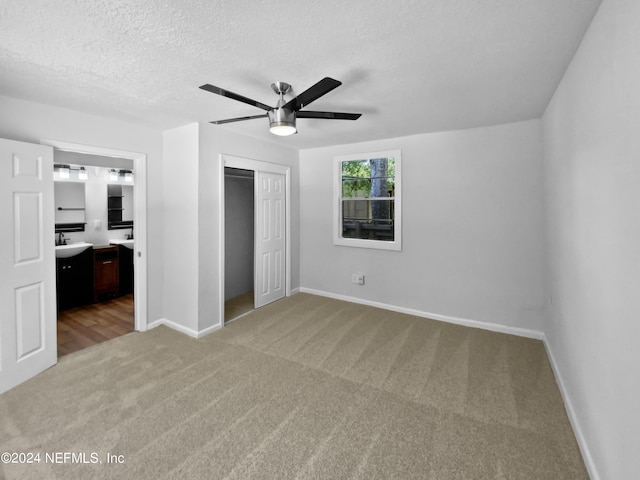 unfurnished bedroom featuring ceiling fan, a closet, carpet flooring, a textured ceiling, and connected bathroom