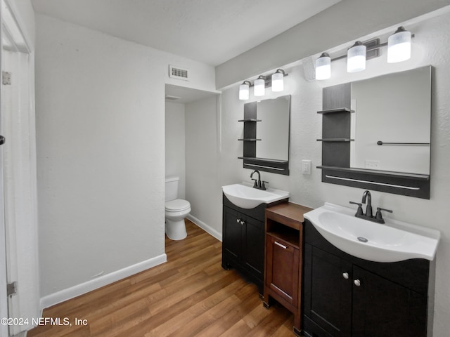 bathroom featuring double vanity, toilet, and hardwood / wood-style floors