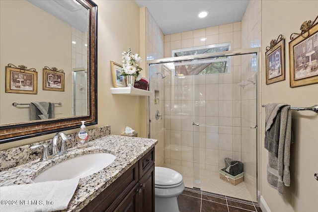 bathroom with a shower with shower door, oversized vanity, toilet, and tile floors