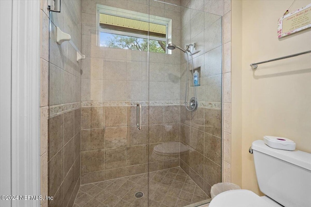 bathroom with a shower with door and toilet