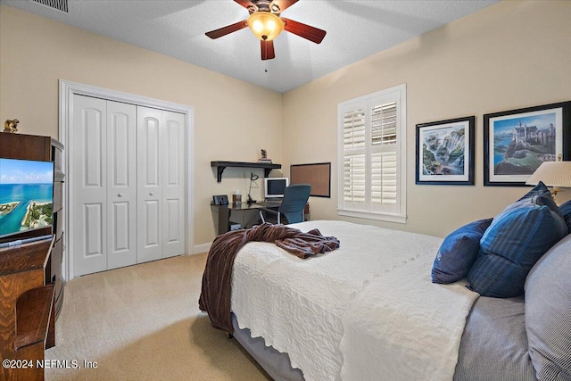 carpeted bedroom with a textured ceiling, a closet, and ceiling fan