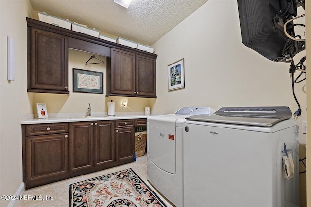 washroom with washer and dryer, a textured ceiling, light tile floors, sink, and cabinets