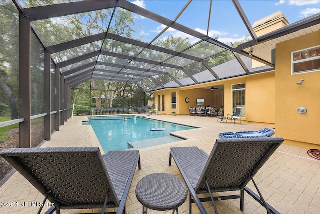 view of pool featuring ceiling fan, glass enclosure, and a patio