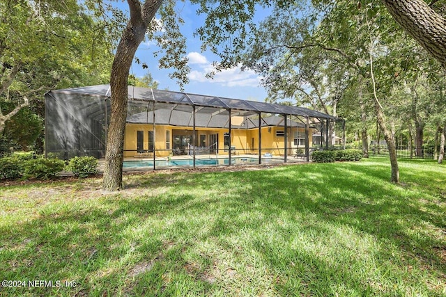 rear view of house with a lanai and a yard