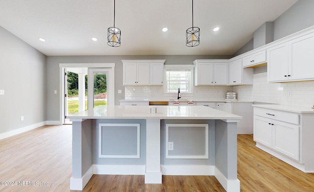 kitchen with a center island, decorative light fixtures, tasteful backsplash, and light hardwood / wood-style flooring