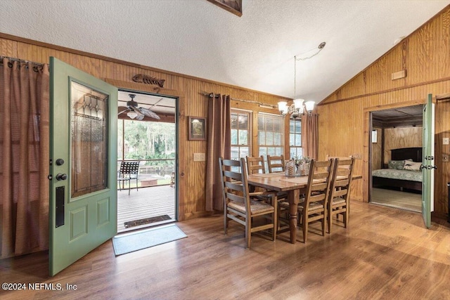 dining area with wood walls, hardwood / wood-style flooring, a textured ceiling, and lofted ceiling