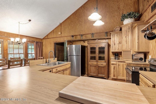 kitchen with stainless steel appliances, wood walls, sink, and high vaulted ceiling