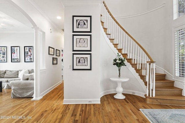 stairs featuring crown molding, hardwood / wood-style flooring, and ornate columns