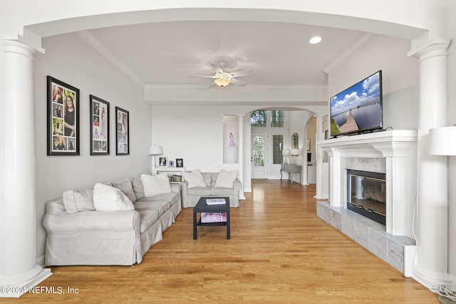 living room featuring ornate columns, ornamental molding, and light wood-type flooring